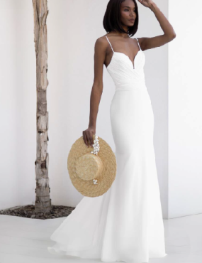 A woman in a white dress is holding a straw hat