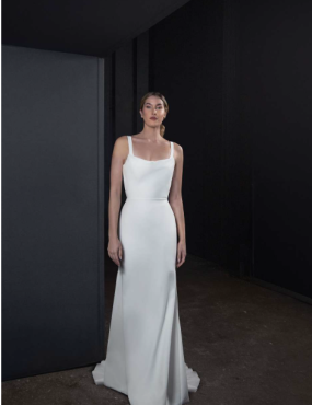 A woman in a white dress is standing in a dark room.
