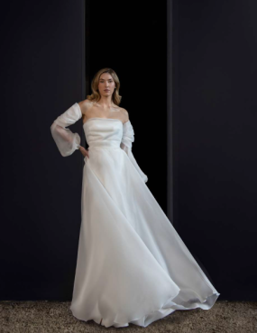 A woman in a white wedding dress is standing in a doorway.