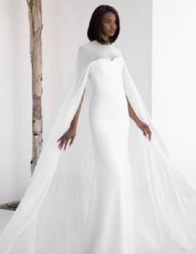 A woman is wearing a white wedding dress with a cape.