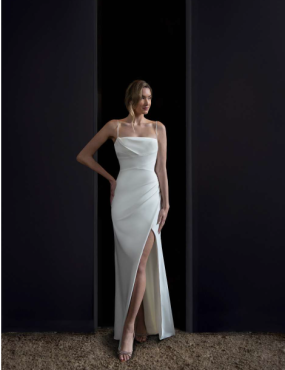 A woman in a white dress is standing in a doorway.