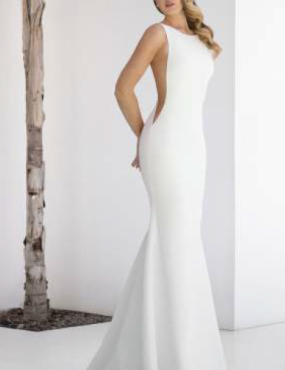 A woman in a white wedding dress is standing next to a tree.