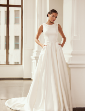 A woman in a white wedding dress is standing in front of a window