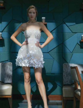 A woman in a white dress is standing in front of a blue wall