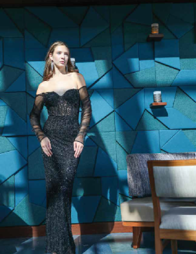 A woman in a black dress is standing in front of a blue wall