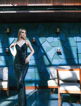 A woman in a long black dress is standing in a room with chairs.