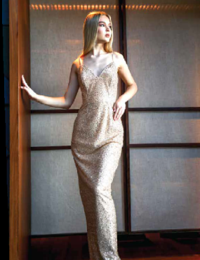 A woman in a long dress is leaning against a wall