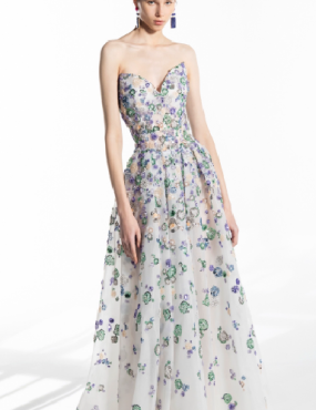 A woman is wearing a white dress with blue and green flowers on it