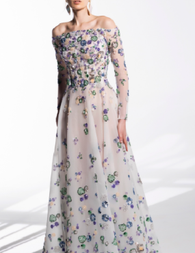 A woman is wearing a white dress with purple and green flowers on it