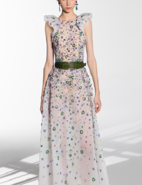 A woman is wearing a long white dress with a green belt.