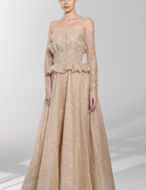 A woman is wearing a long beige dress with long sleeves