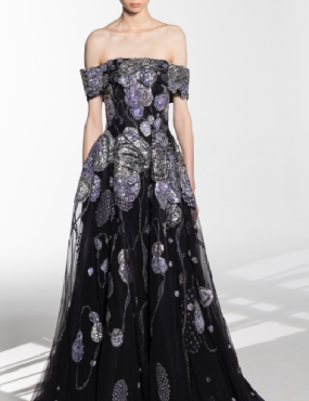 A woman is wearing a black dress with purple flowers on it