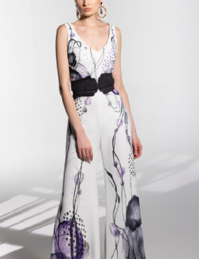 A woman is wearing a white jumpsuit with purple flowers on it