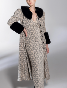 A woman is wearing a long coat with a fur collar and cuffs