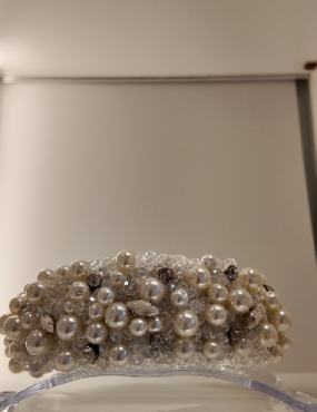 A headband made of pearls and crystals is sitting on a table.