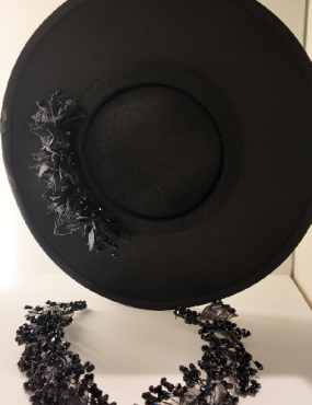 A black hat and necklace are on a table