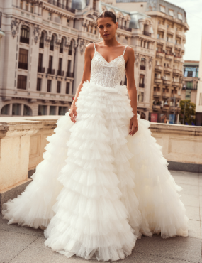 A woman in a white wedding dress is standing on a balcony.