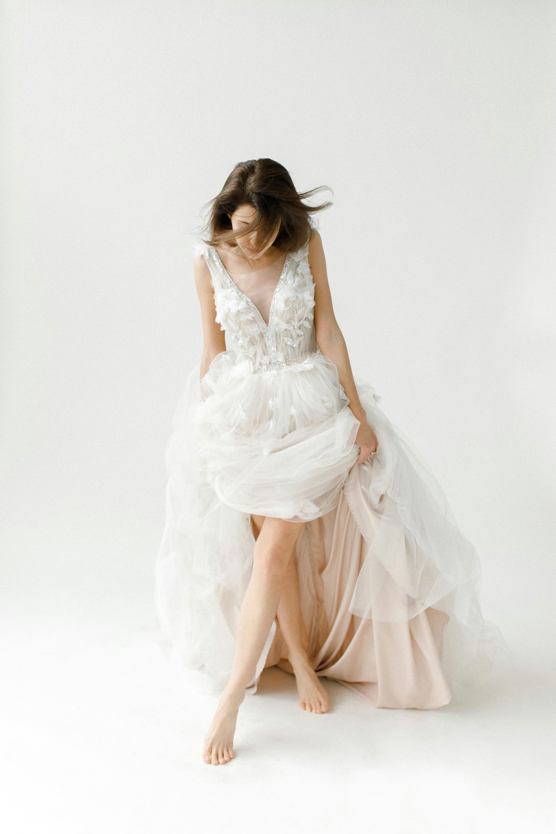 A woman in a wedding dress is sitting on the floor with her legs crossed.