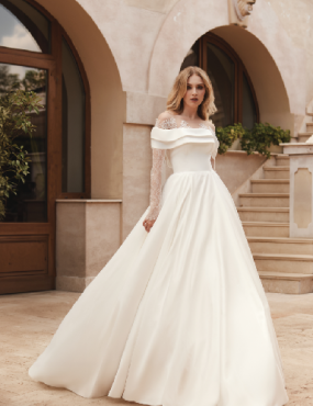 A woman in a white wedding dress is standing in front of a building.