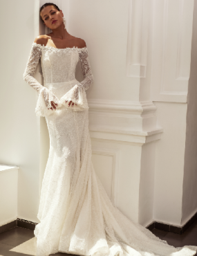 A woman in a wedding dress is leaning against a wall