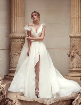 A woman in a white wedding dress is standing in front of columns.