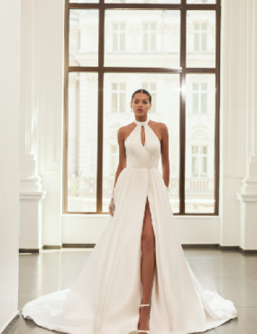 A woman in a white wedding dress is standing in front of a window.