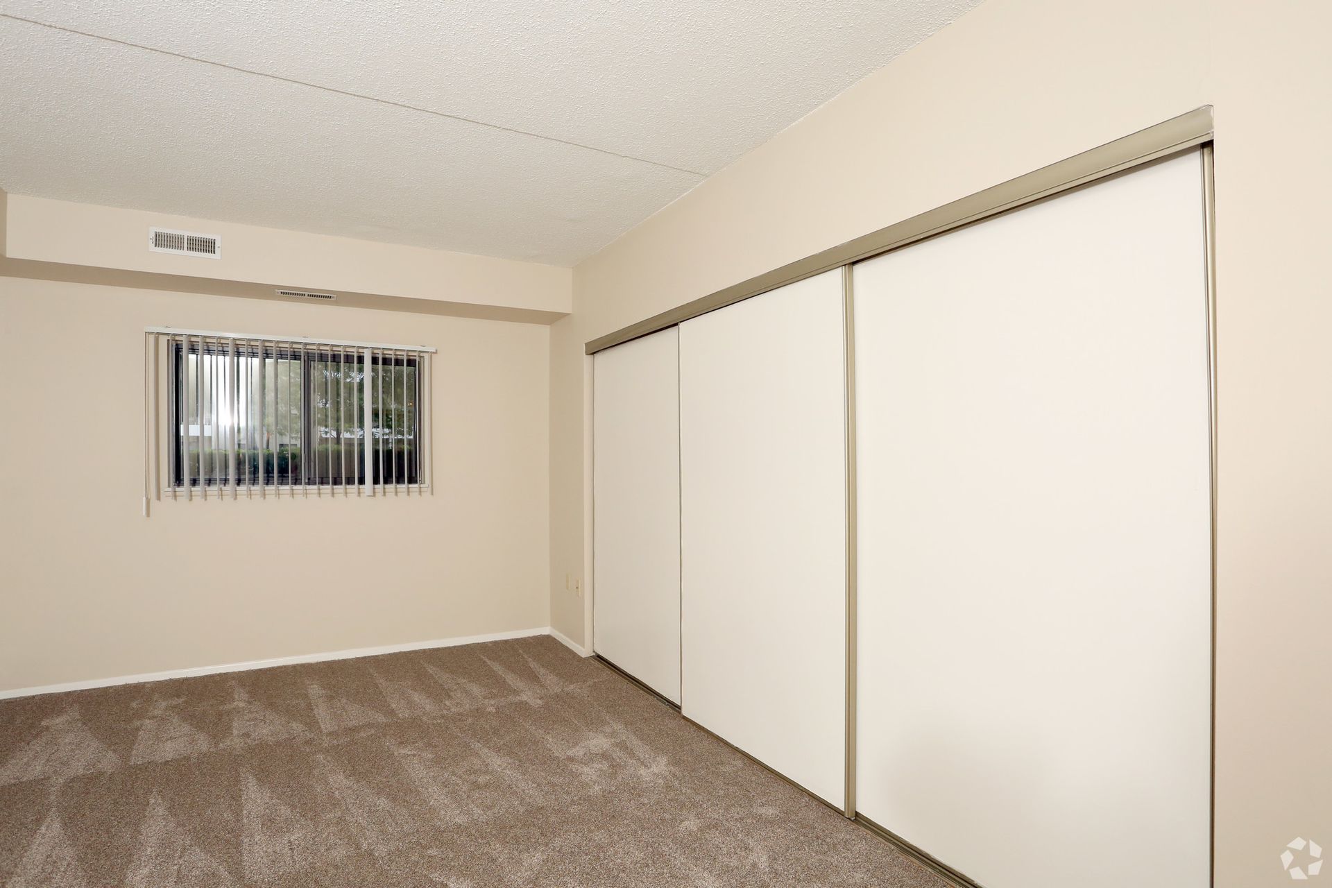 An empty room with a window and white sliding doors
