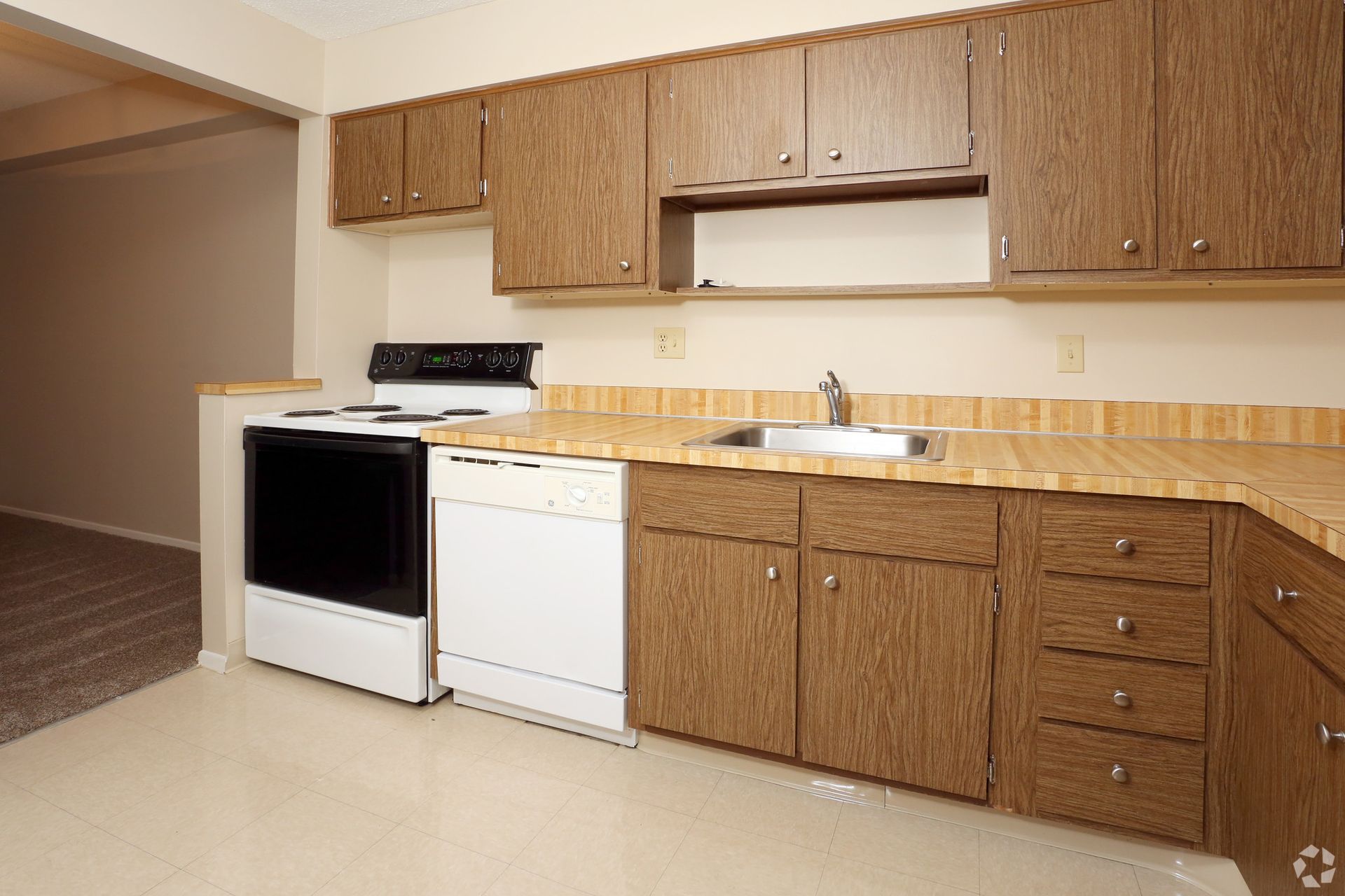 An empty kitchen with wooden cabinets and a white stove