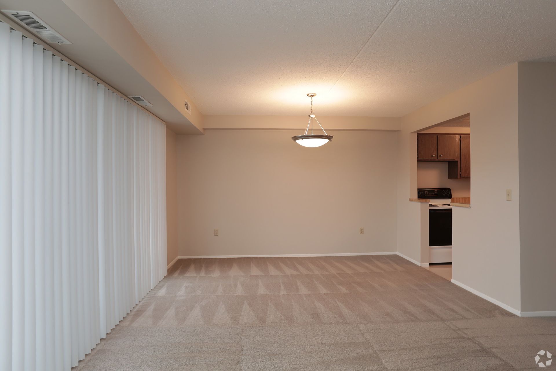 An empty living room with a chandelier hanging from the ceiling