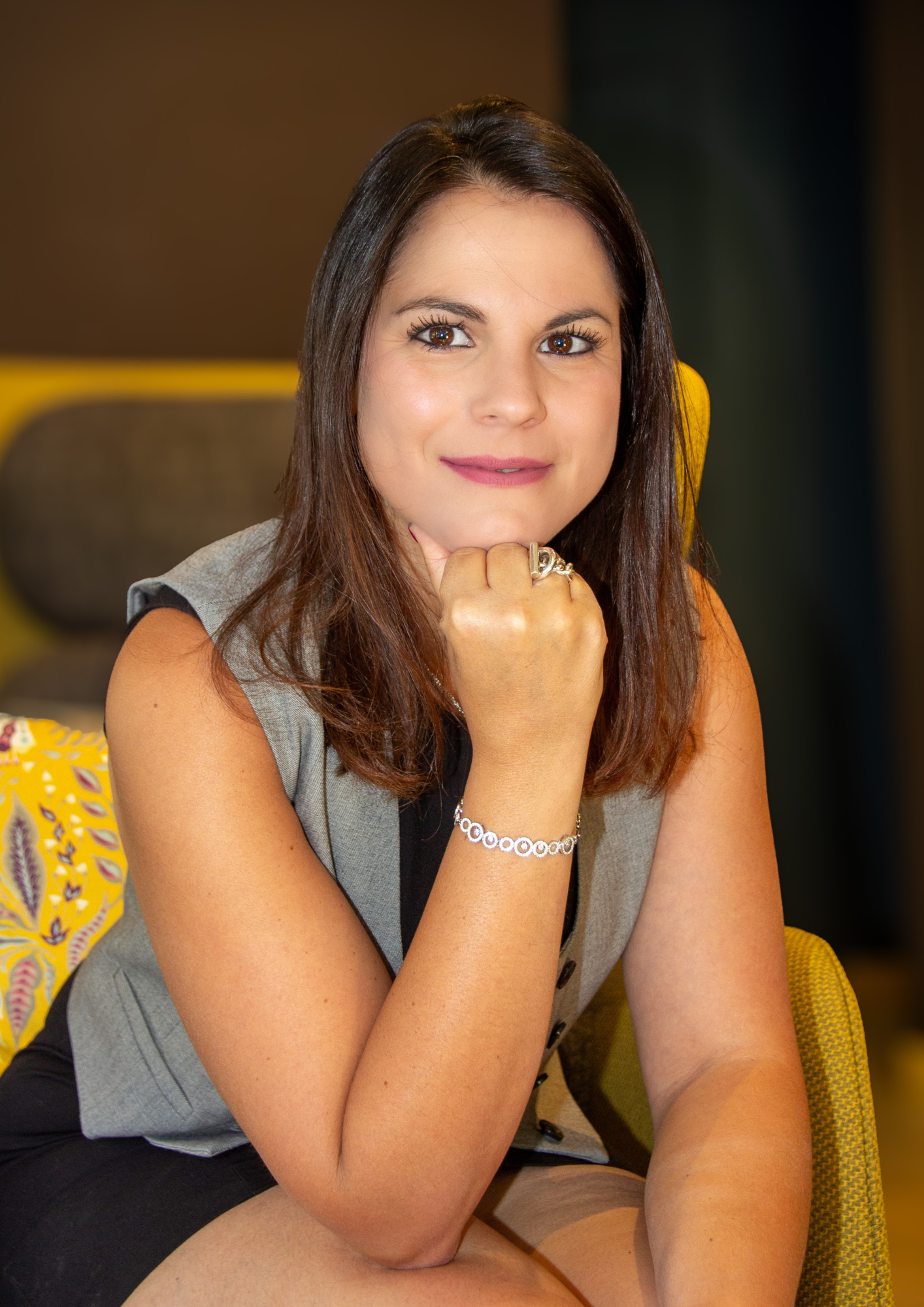 Femme en débardeur, le menton appuyé sur la main, regardant l'objectif. Assise, expression neutre.