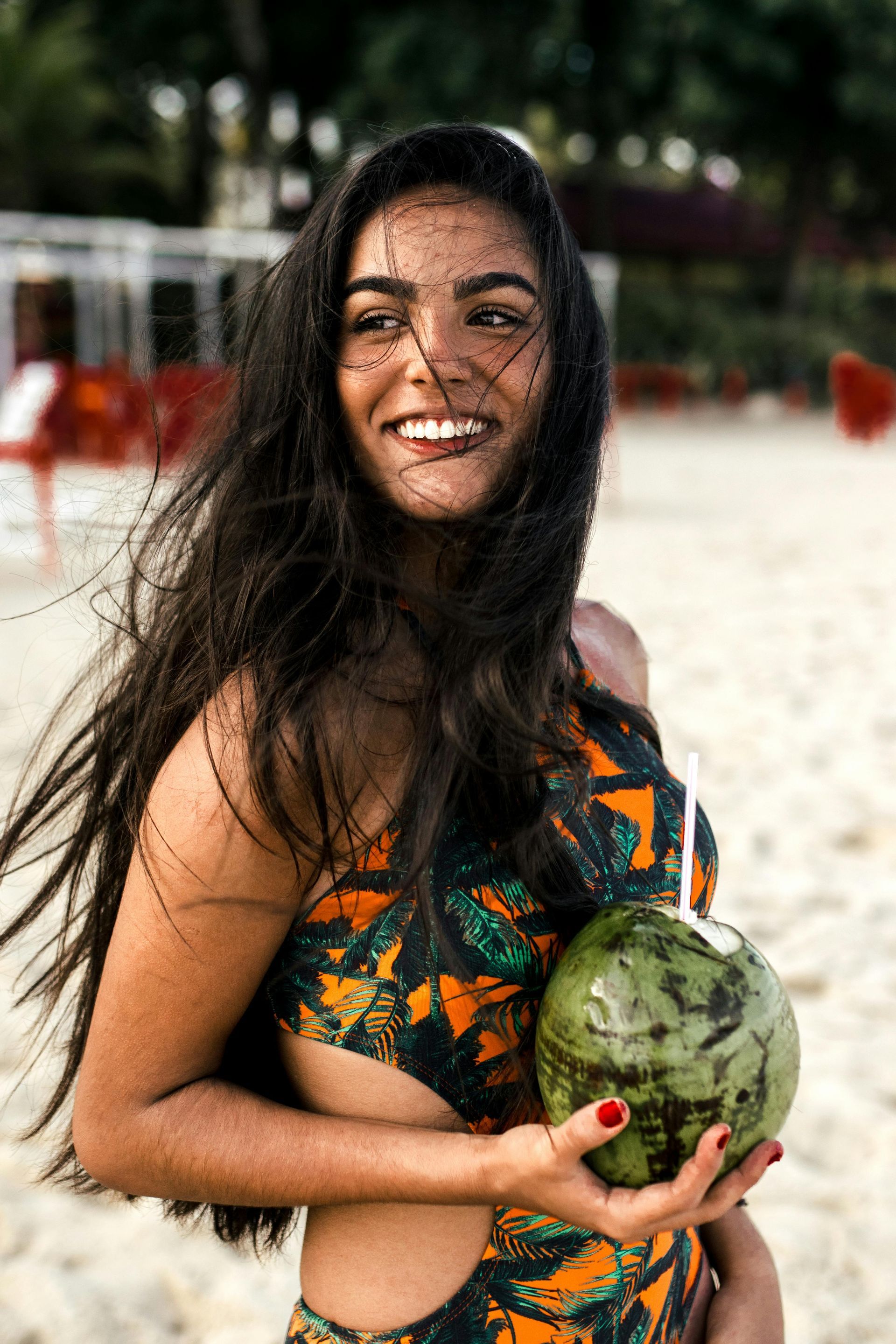 A woman in a swimsuit is holding a coconut on the beach.