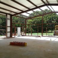 An interior view of a steel-framed building under construction with a concrete floor and a red ladder in the foreground.