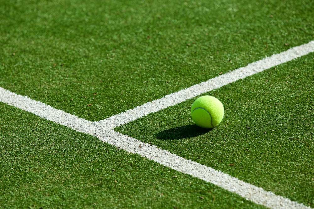 Tennis Ball On Tennis Grass Court — Professional Pool Builder in Gundagai, NSW