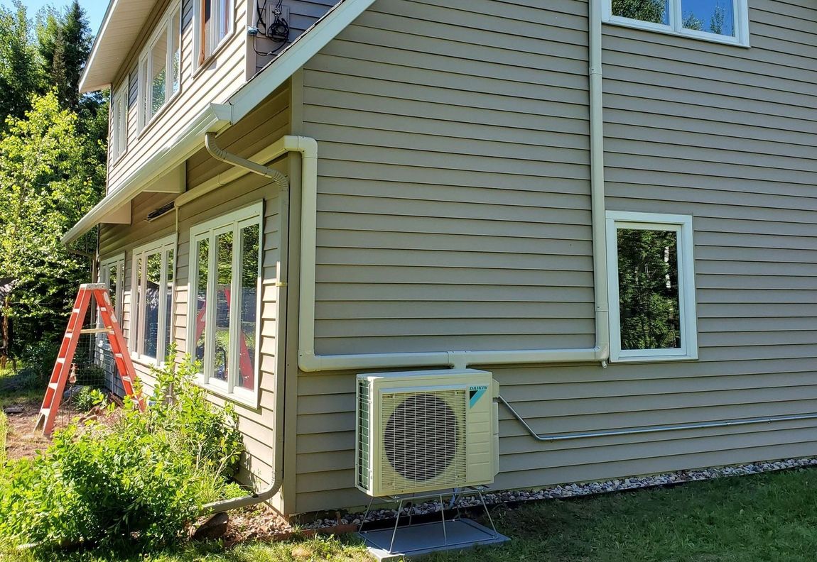 A person is holding a gauge in front of an air conditioner.