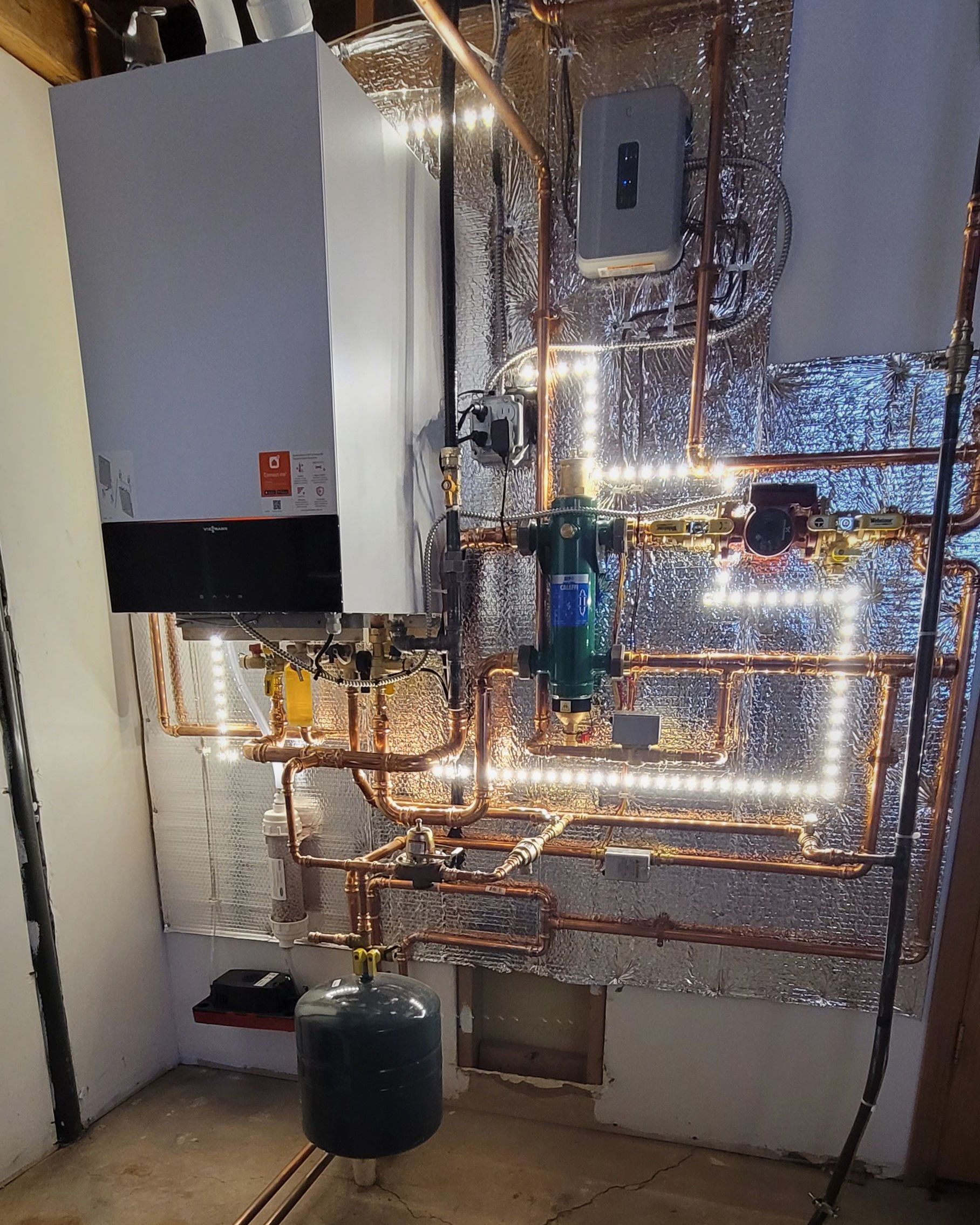 A room with a boiler and pipes in it.