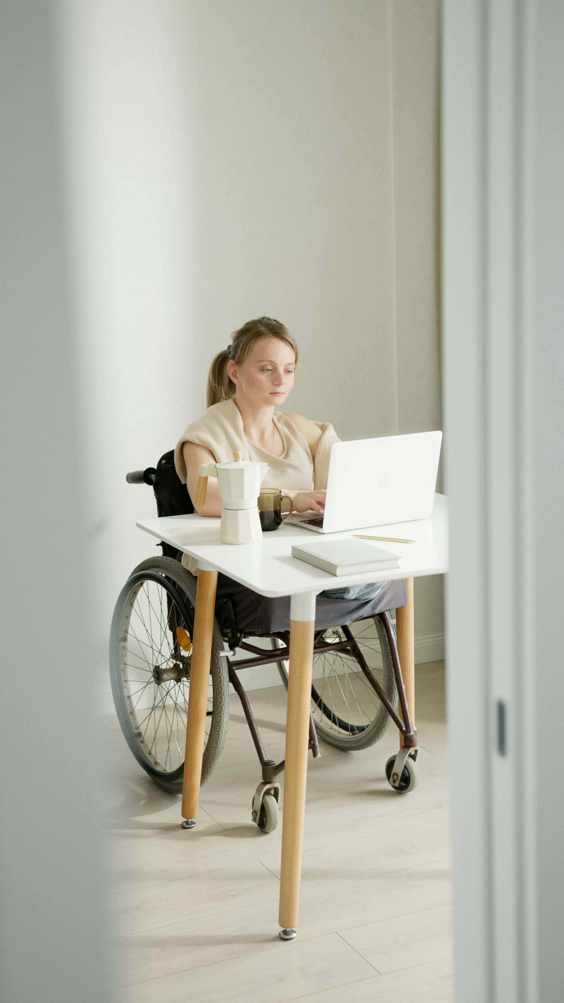 Person utilizing a manual wheelchair while sitting at an at home work desk