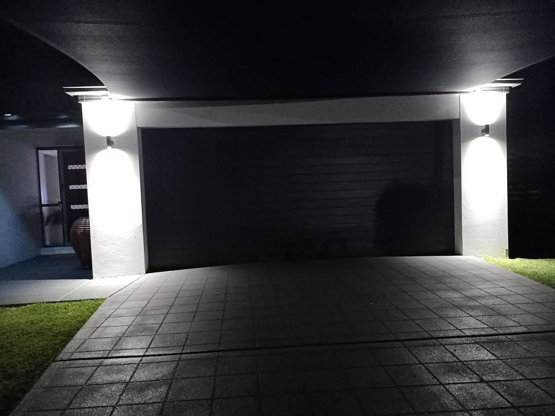Illuminated driveway and garage lighting setup at night.