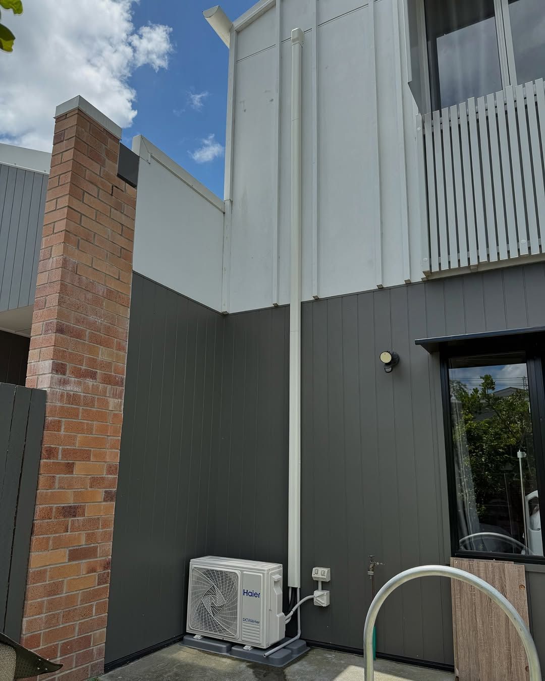 Outdoor lighting installed on a grey residential building facade.