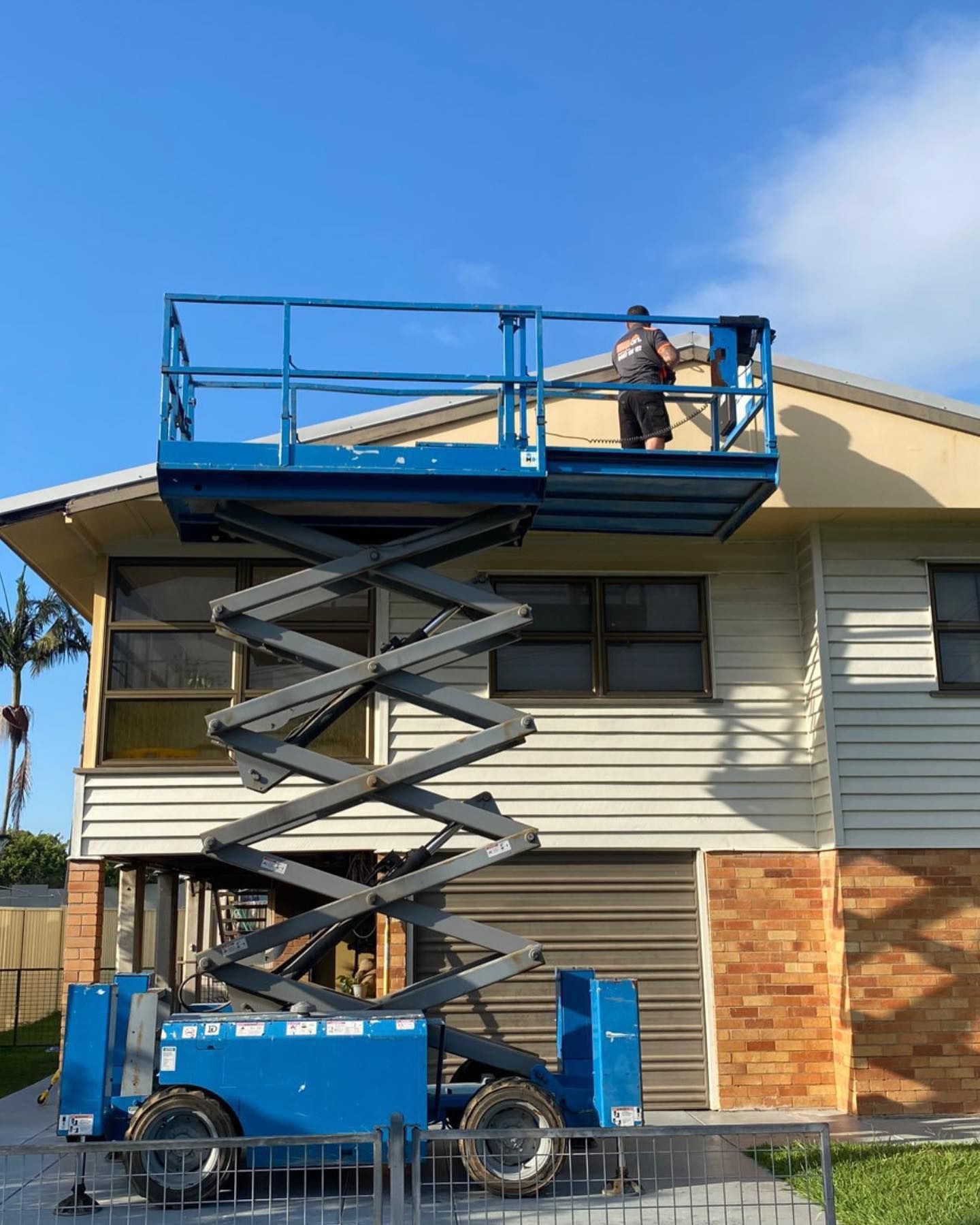 Brisbane electrician on scissor lift performing exterior lighting maintenance