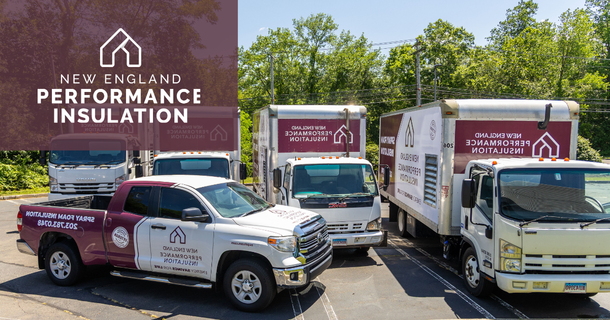 A row of white and maroon business trucks and a pickup truck parked on an asphalt lot outdoors on a sunny day.