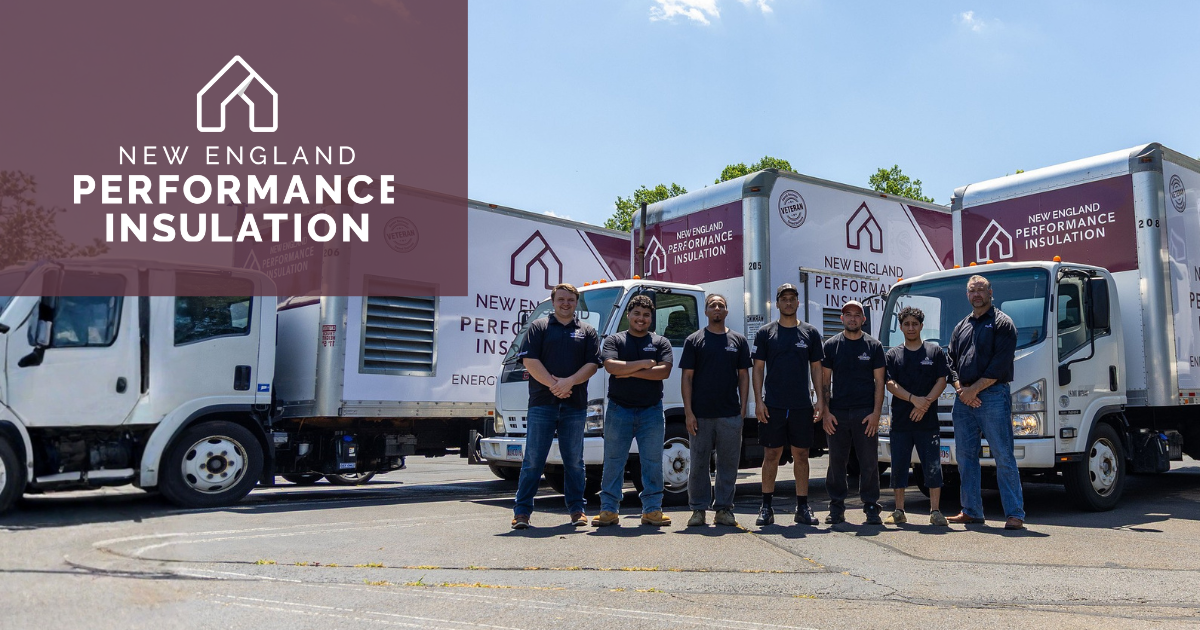 Seven employees wearing dark shirts stand in front of three trucks branded with the New England Performance Insulation logo.