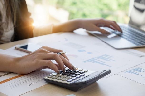 A Woman Is Typing on A Laptop While Using a Calculator — Sunshine Coast Financial Advisers in Maroochydore, QLD