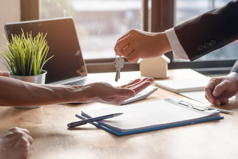 A Man Is Handing a Set of Keys to Another Man — Sunshine Coast Financial Advisers in Maroochydore, QLD