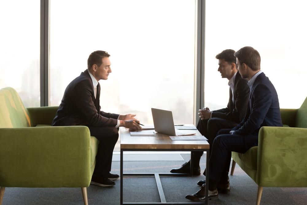 A Group of Businessmen Are Sitting Around a Table with A Laptop — Sunshine Coast Financial Advisers in Maroochydore, QLD
