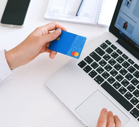 A Person Is Holding a Credit Card in Front of A Laptop Computer — Sunshine Coast Financial Advisers in Maroochydore, QLD