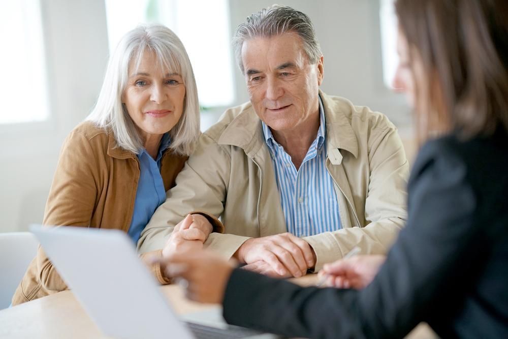 An Elderly Couple Is Sitting at A Table Talking to A Woman — Sunshine Coast Financial Advisers in Maroochydore, QLD