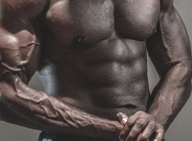 A man without a shirt is holding his arms around his chest.