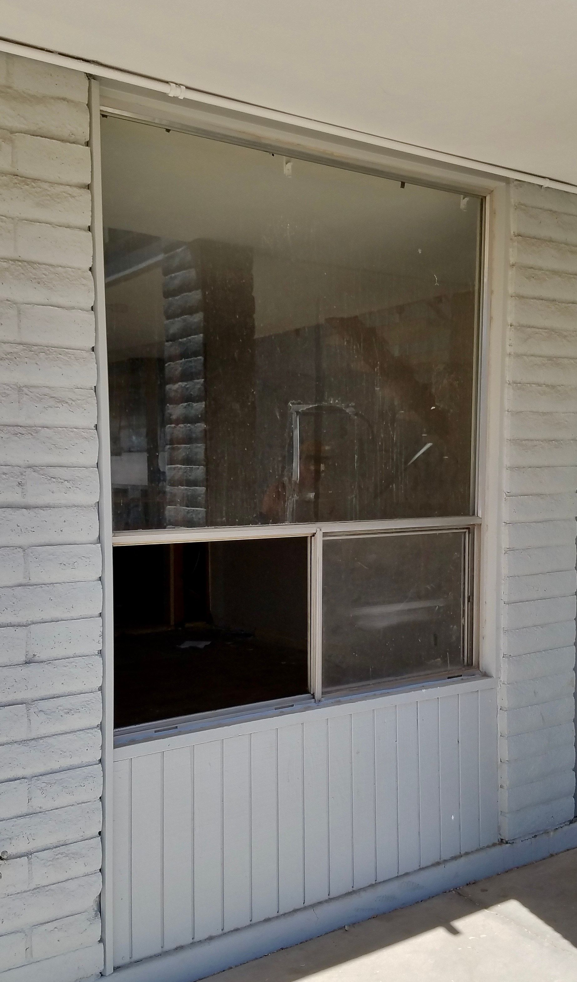 Large, dirty window with a lower section open, set in a white exterior wall.  Interior visible.