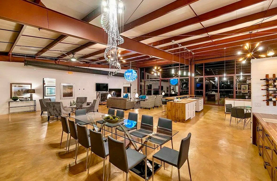Spacious event space with chairs in a semi-circle, couches, and a kitchen area, with a high ceiling and windows.