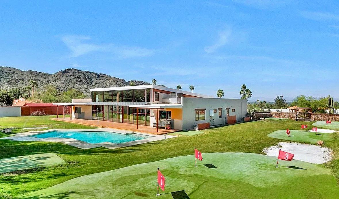 A two-story building with a pool and miniature golf course under a clear blue sky.